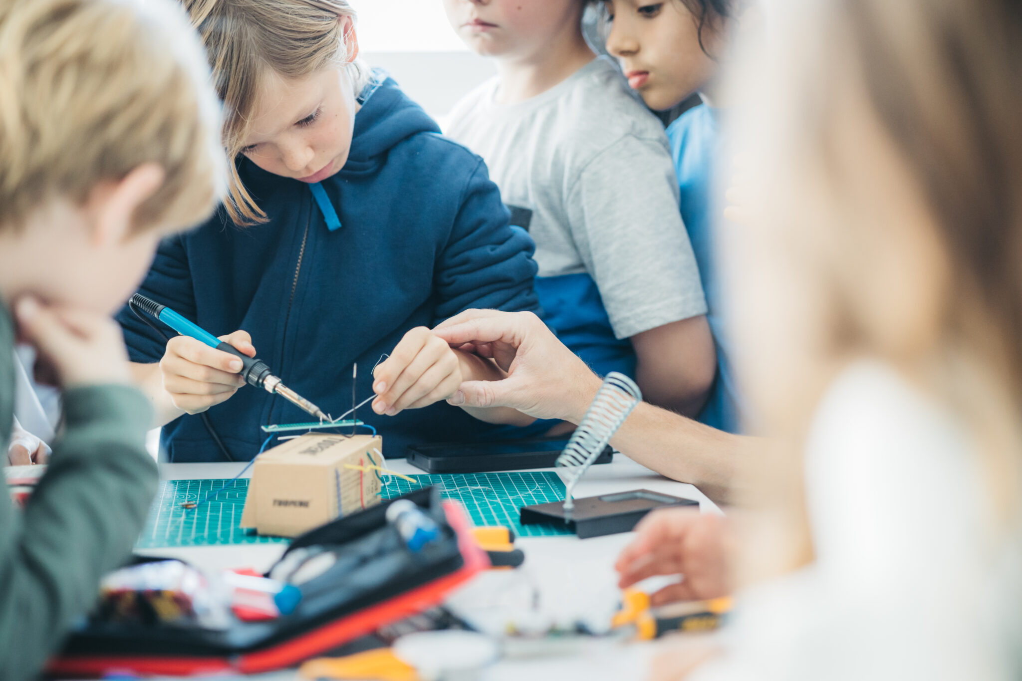 child assembling tech with teacher assistance